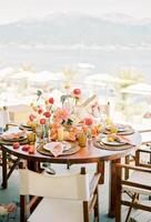 Colorful bouquet on a festive table with halves of oranges and plates on wicker rugs photo