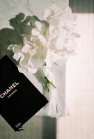 White freesia bouquet lies on a marble table next to a book. Caption. Chanel. Catwalk photo