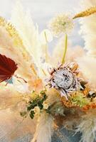 Colorful wedding bouquet with dried flowers stands on the pier. Close-up photo