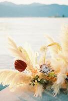 Wedding semi-arch made of dried flowers and bright flowers stands on the pier photo