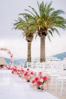 brillante ramos de flores de flores estar a lo largo filas de blanco sillas en frente de el Boda arco foto