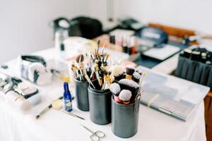 variedad de maquillaje cepillos y bocanadas estar en cuero casos cerca productos cosméticos en el mesa foto