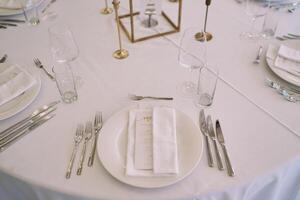 Invitation with a festive menu wrapped in a napkin lies on a plate on a set table photo