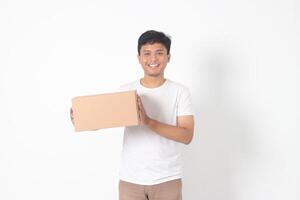 Portrait of attractive Asian man in white tshirt carrying a cardboard box. Isolated image on white background photo