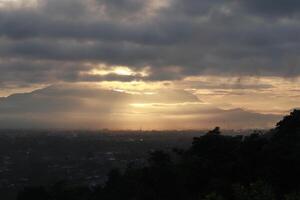 dramático amanecer con oscuro nubes en el cielo terminado el montañas, gorontalo, Indonesia foto