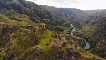 aereo panning Visualizza drammatico paesaggio con storico tmogvi fortezza rovine con vecchio parete su cima circondato panoramico mtkvari fiume e canyon panorama video