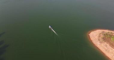 Aerial drone view following the long tail boat in a dam video