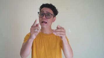 Young Indonesian curly man wear yellow t-shirt and glasses angry expression.  The footage is suitable to use for man expression and daily life content media. video