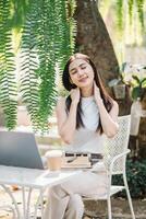 mujer toma un relajante descanso desde trabajar, disfrutando el tranquilo ambiente de un al aire libre jardín cafetería. foto