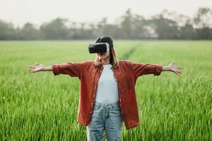 A woman wearing a VR headset stands in a field of grass photo