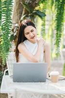 Woman takes a relaxing break from work, enjoying the tranquil environment of an outdoor garden cafe. photo