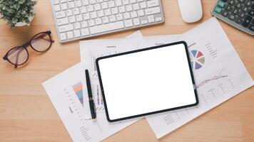 A tablet sits on top of a stack of papers with a pen on the table. The scene suggests a work environment where someone is working on a project or task photo