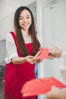 A woman with a beaming smile receives a red envelope, a gesture steeped in cultural significance, conveying blessings and good fortune. photo