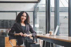 Confident young businesswoman at a cafe with laptop and smartphone, ready for a productive workday. photo