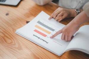 Close up of a professional hands pointing at a growth chart while analyzing business performance in a detailed report. photo