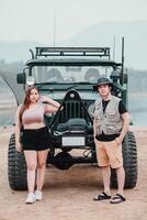 joven Pareja poses con confianza junto a su escabroso todoterreno auto, Listo para un aventuras en el genial al aire libre. foto