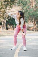 un joven atleta toma un momento a frio abajo, limpiando sudor desde su frente después un vigoroso rutina de ejercicio en un parque camino, ilustrando el importancia de descanso en aptitud regímenes. foto