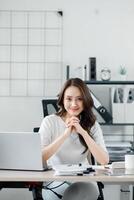 Smiling businesswoman sits confidently at her tidy desk in a modern, well-lit office environment. photo