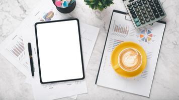 A tablet and a cup of coffee sit on a table with several pieces of paper. The scene suggests a moment of relaxation or contemplation photo