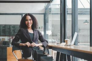 Confident young businesswoman at a cafe with laptop and smartphone, ready for a productive workday. photo