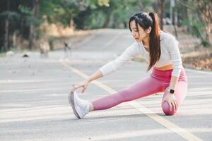 Young woman doing a hamstring stretch on a quiet park road, enjoying a morning fitness routine. photo