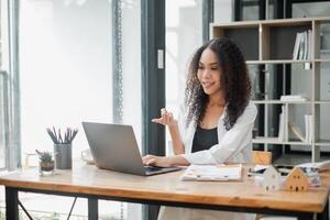 Animated young businesswoman engaging in a lively conversation during a virtual meeting in a sunny, modern workspace. photo