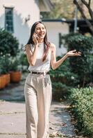 Joyful businesswoman has a pleasant conversation on her phone while walking in a lush garden setting. photo