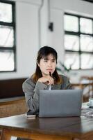 profundo en pensamiento, un mujer de negocios evalúa su trabajo en un ordenador portátil a un elegante cafetería, encarnando moderno emprendimiento foto