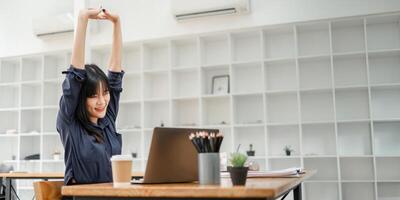 Young businesswoman enjoying a stretching break at her desk to rejuvenate during a busy workday at the office. photo