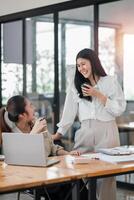 Two professional women sharing a light-hearted moment and a laugh over a coffee break in a bright, modern office setting. photo