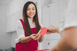 A woman with a beaming smile receives a red envelope, a gesture steeped in cultural significance, conveying blessings and good fortune. photo