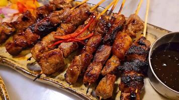 caseiro carne satay marinado com especiaria e doce soja molho, coentro carne satay, servido em prato com cebola, Pimenta, soja molho e tomate. indonésio tradicional Comida video