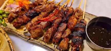 Homemade beef Satay marinated with spice and sweet soy sauce, coriander beef satay, served on plate with onion, chilli, soy sauce and tomato. Indonesian traditional food video