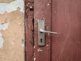 el Perilla de la puerta en un marrón puerta estaba oxidado y podría No más extenso ser cerrado foto