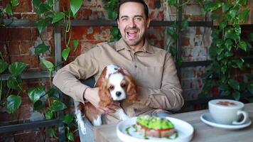 A man with a dog in a cafe . Dog friendly establishments video