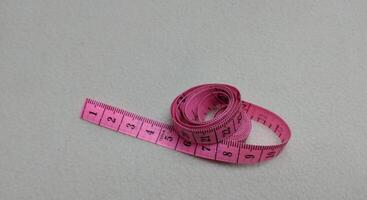 Pink measuring tape isolated on white background with copy space for text. photo