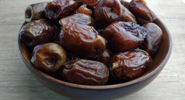 Dates fruit in a wooden bowl on a wooden background. Top view. photo