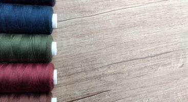 Spools of multicolored thread on wooden background with copy space photo