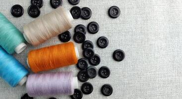 Spools of thread and buttons on a gray background, top view photo