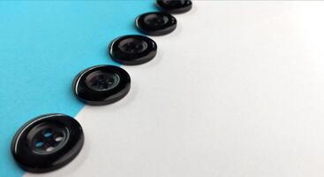 Black buttons on a white and blue background. Selective focus. photo