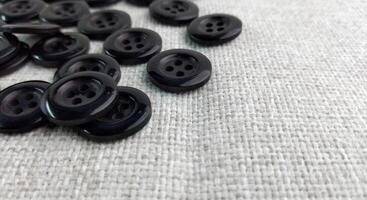 Black sewing buttons on white fabric background. Flat lay, top view. photo