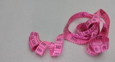 Pink measuring tape isolated on white background with copy space for text. photo