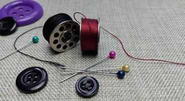 spool of thread, pins and buttons for sewing on a gray background photo