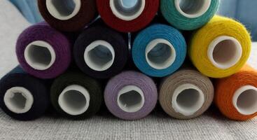 rollos de multicolor hilos para sastres trabajando en el prenda bordado sector foto