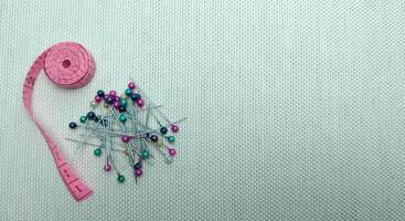 sewing needles and pins of different colors, ruler on white cloth background photo