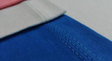 Fabric samples in different shades of blue and pink, closeup on green background photo