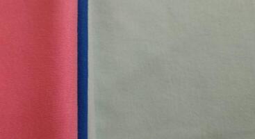 Fabric samples in different shades of blue and pink, closeup on green background photo
