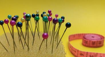 colorful pins and measuring tape on a yellow background. photo