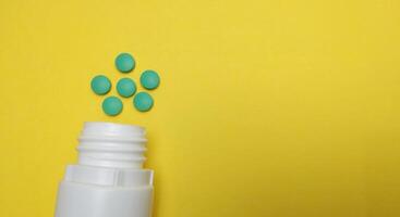 various kinds of pills arranged abstractly on a yellow background photo