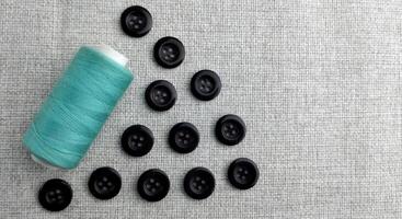 Spools of thread and buttons on a gray background, top view photo